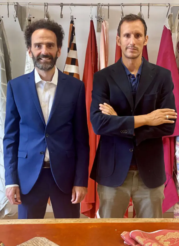Andrea e Filippo Taborelli in giacca blu davanti a un campionario di tessuti