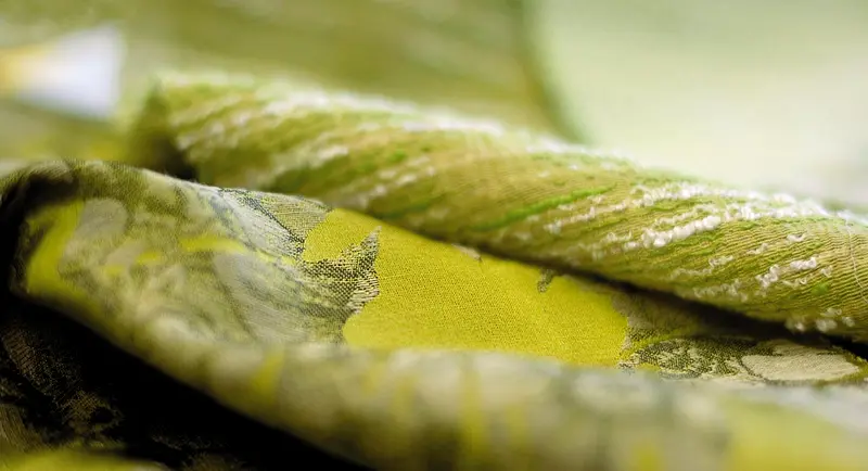 Primo piano di un broccato verde e oro con un filo ritorto in rilievo